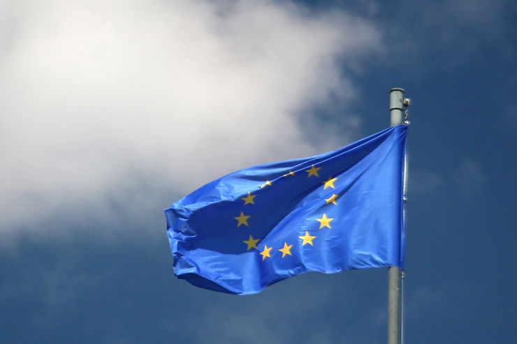 The EU flag against a cloudy blue sky